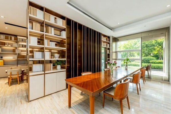 A modern dining area with a long wooden table, chairs, and a built-in bookshelf. - Easy Go Inn (Shanghai Hangtou Hunan Highway Store) (Shanghai)