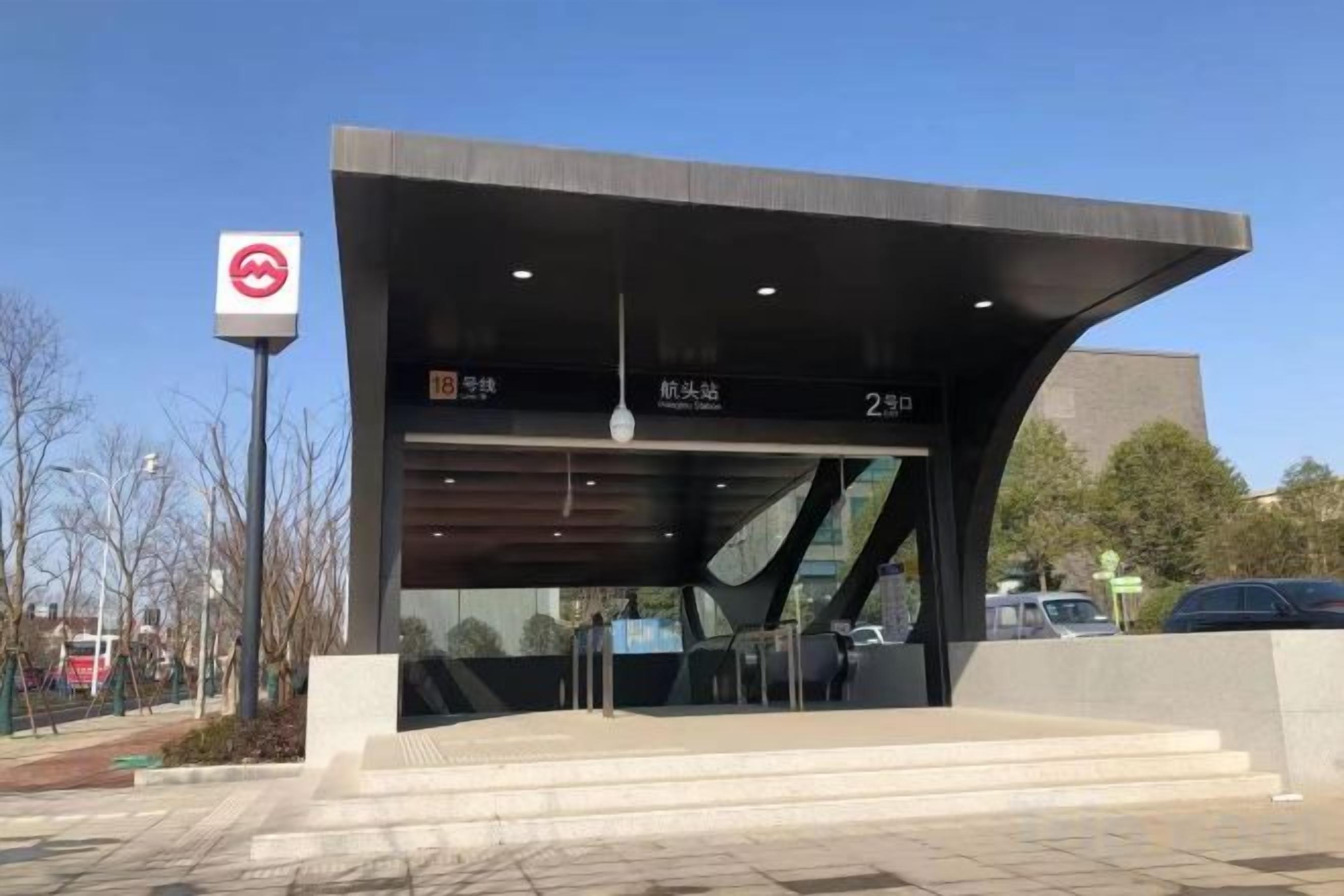 A modern building with a curved roof, a sign indicating a location, and a staircase leading to the entrance.