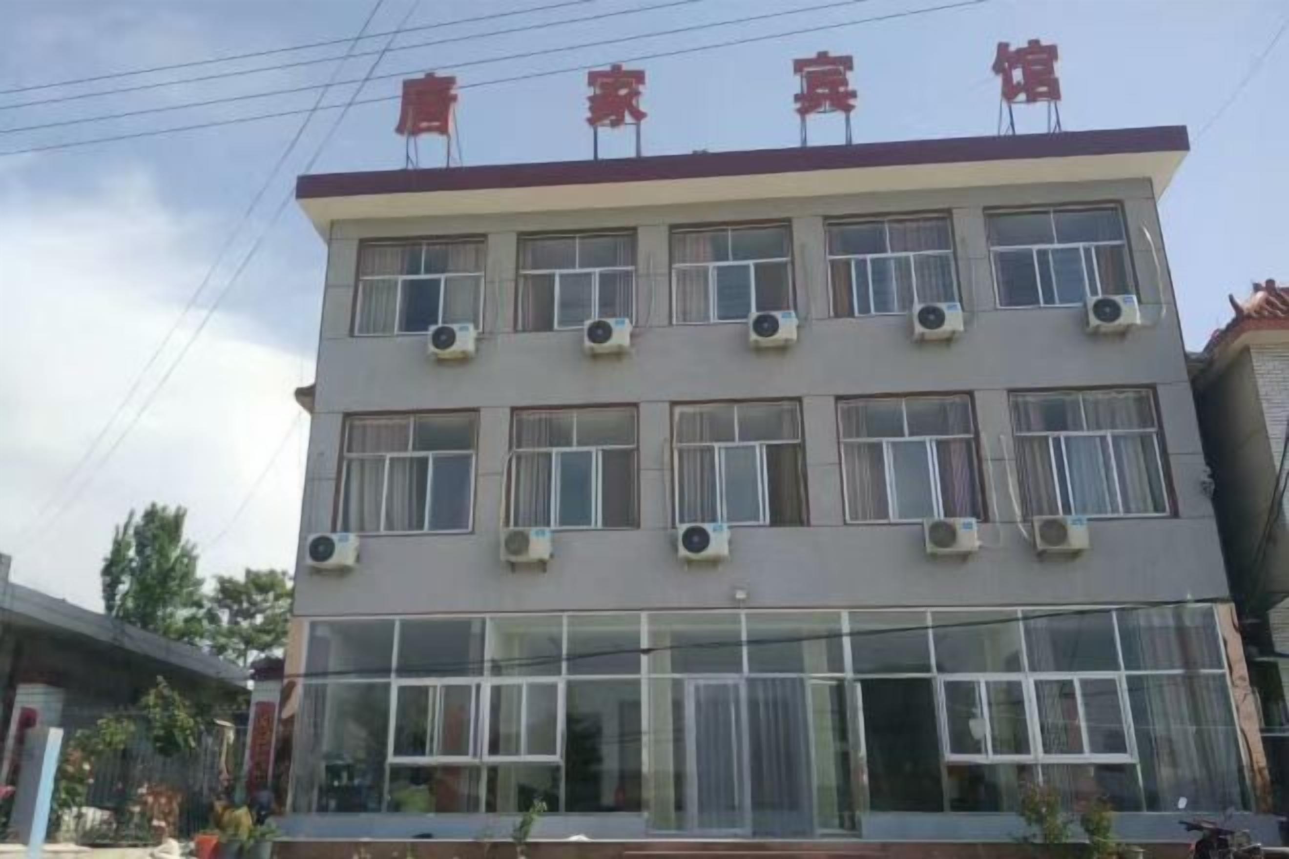 A multi-story hotel with air conditioning units on each floor, large windows, and a sign with Chinese characters.