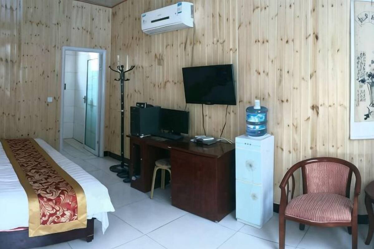 A hotel room with a bed, desk, chair, TV, and a water dispenser.