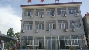 Un hôtel à plusieurs étages, doté d’un toit plat et de climatiseurs sur chaque étage.
