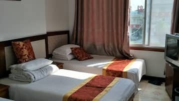 Ein Hotelzimmer mit zwei Betten, einem Fernseher und einem Fenster mit Vorhängen.