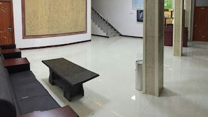Un hall d’entrée agrémenté d’une grande œuvre d’art abstraite, d’un escalier, d’un comptoir de réception et d’un espace salon avec une table basse.