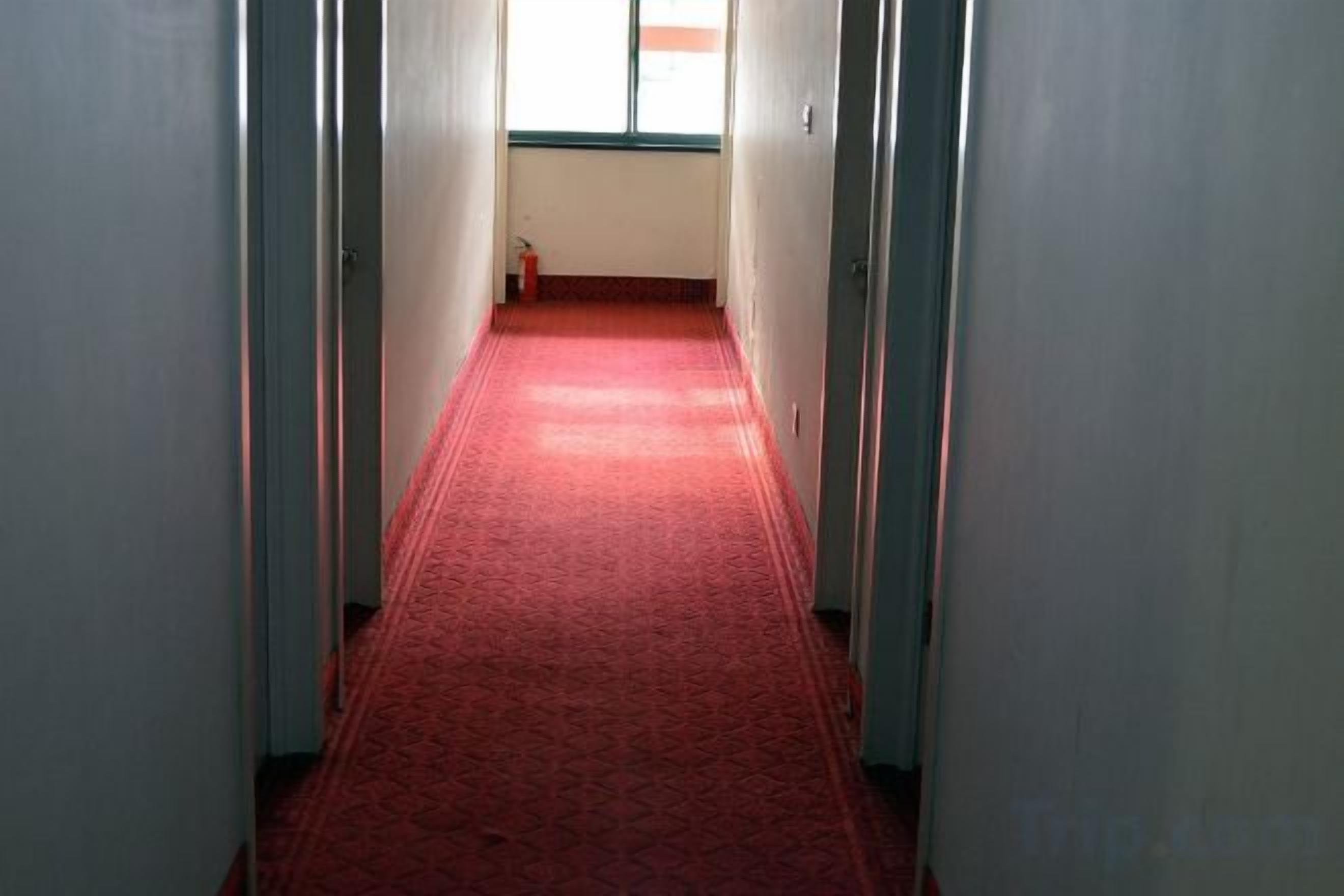 A corridor with a red carpet leading to a door at the end.