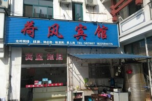 A hotel with a prominent blue signboard displaying the name and contact information. - Hefeng Hotel (Jing County)