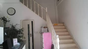 A staircase with a handrail, a door, and a clock on the wall.