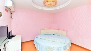 A bedroom with pink walls, a white ceiling, and a bed with a floral bedspread. - Hefeng Hotel (Jing County)