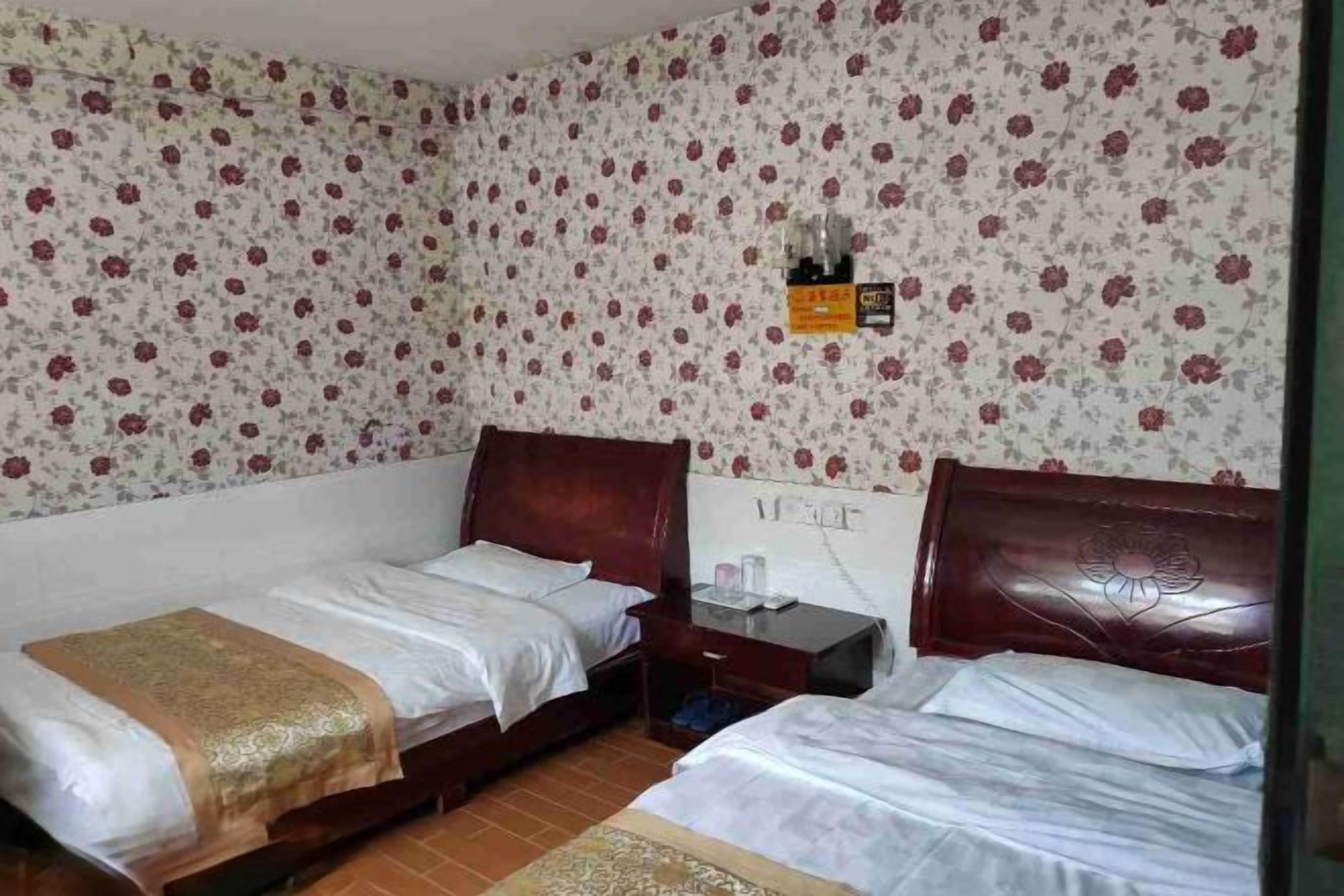 Habitación con dos camas, cabecero de madera, mesita de noche y una repisa en la pared con una botella.