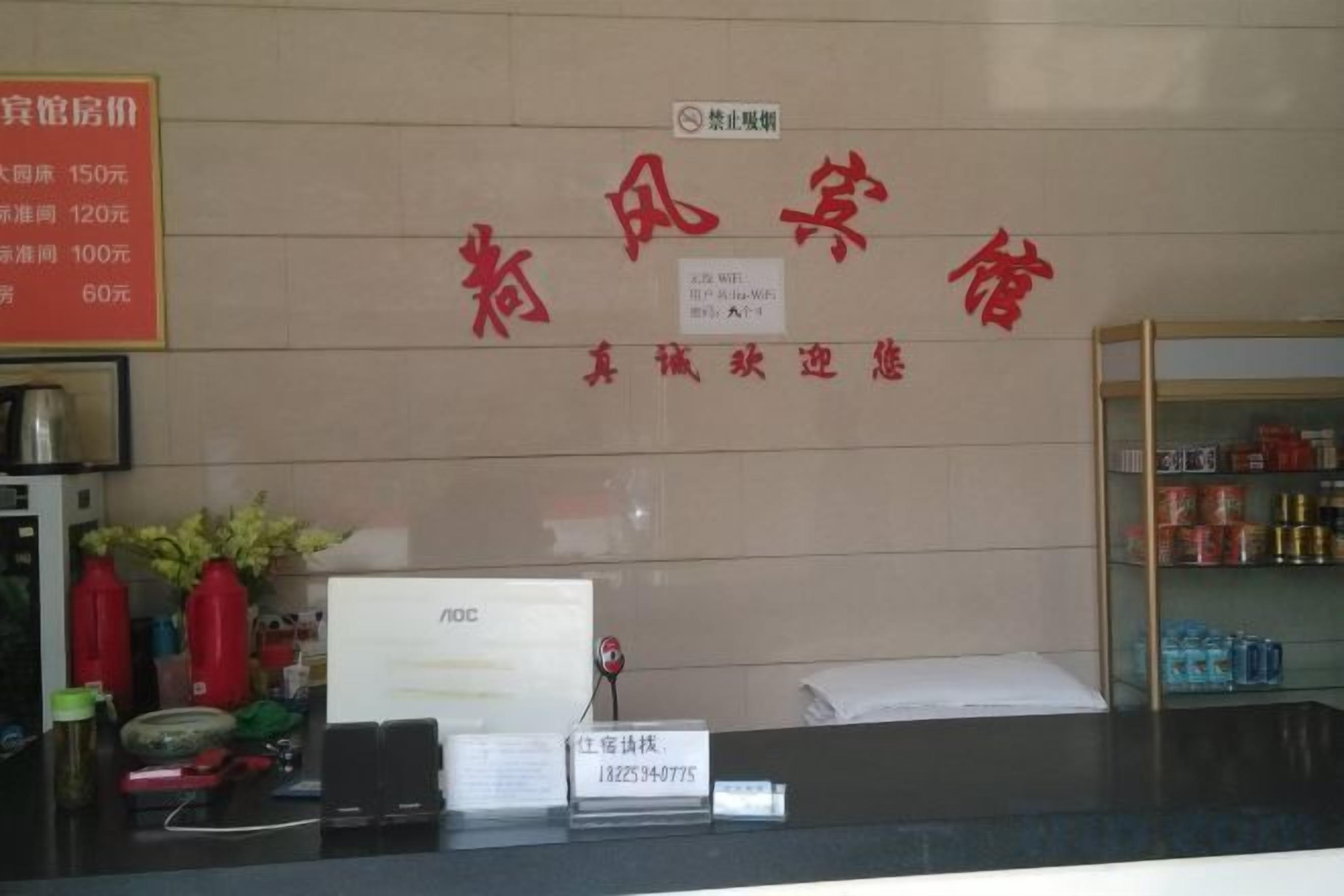 Ein Hotelrezeptionstresen mit einem Schild, das Zimmerpreise anzeigt, und einem digitalen Bildschirm.