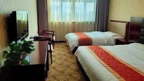 Ein Hotelzimmer mit zwei Betten, einem Schreibtisch, einem Stuhl, einem Fernseher und einer Zimmerpflanze.