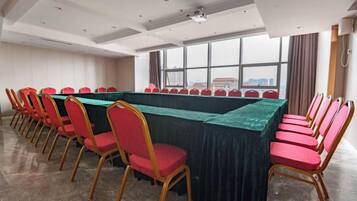 A conference room with a long table, red chairs, and a view through large windows.