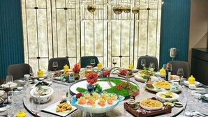 A round table set for a meal with various dishes and drinks, surrounded by chairs and a decorative backdrop. - Heng Da Hotel (Yulin Railway Station Zhongyaogang) (Yulin)