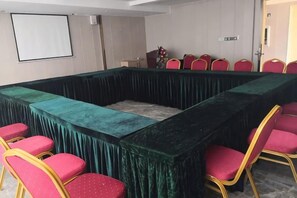 A conference room with a long table, red chairs, and a projector screen. - Heng Da Hotel (Yulin Railway Station Zhongyaogang) (Yulin)