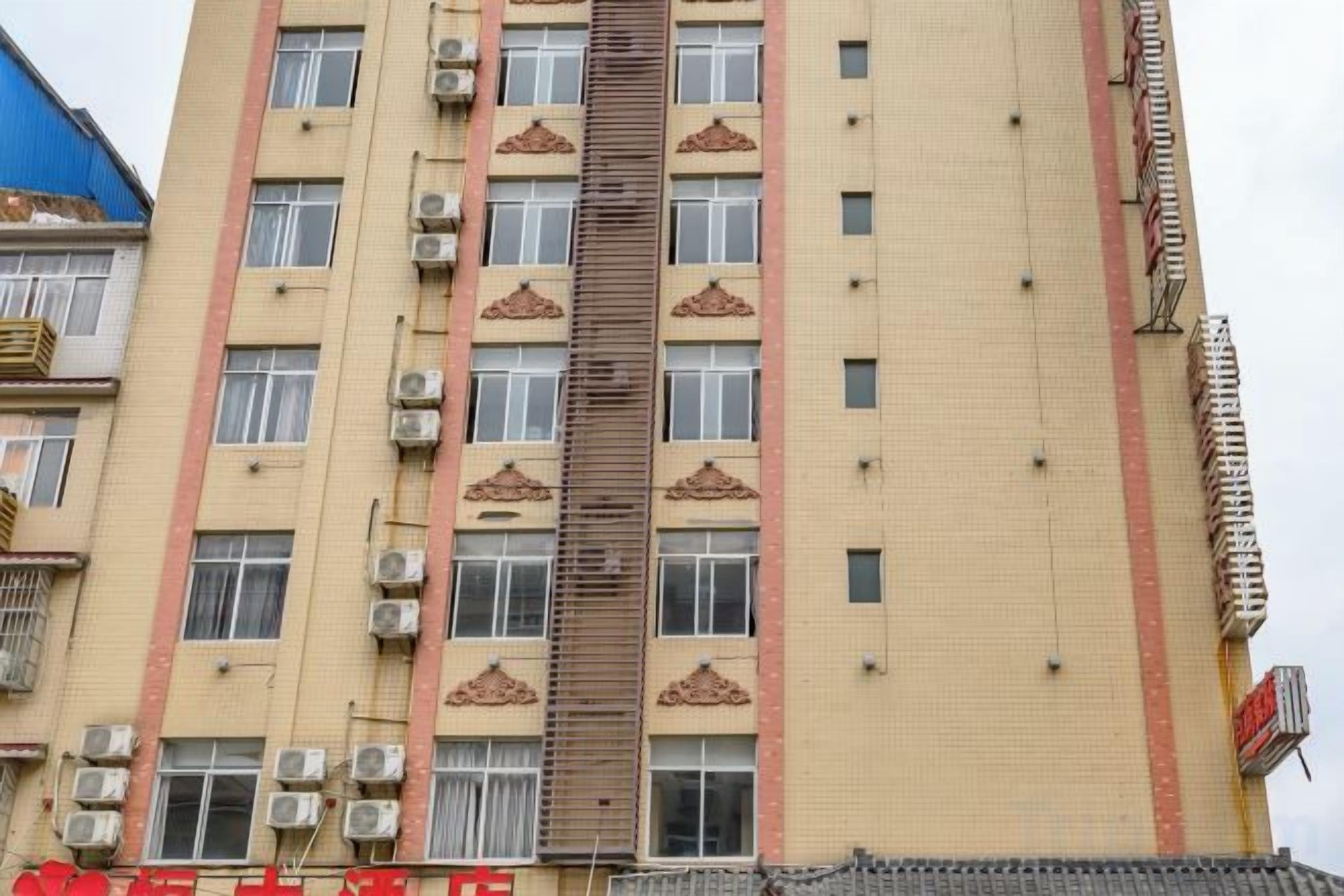 Un edificio a più piani con condizionatori, una scala centrale e diverse finestre.