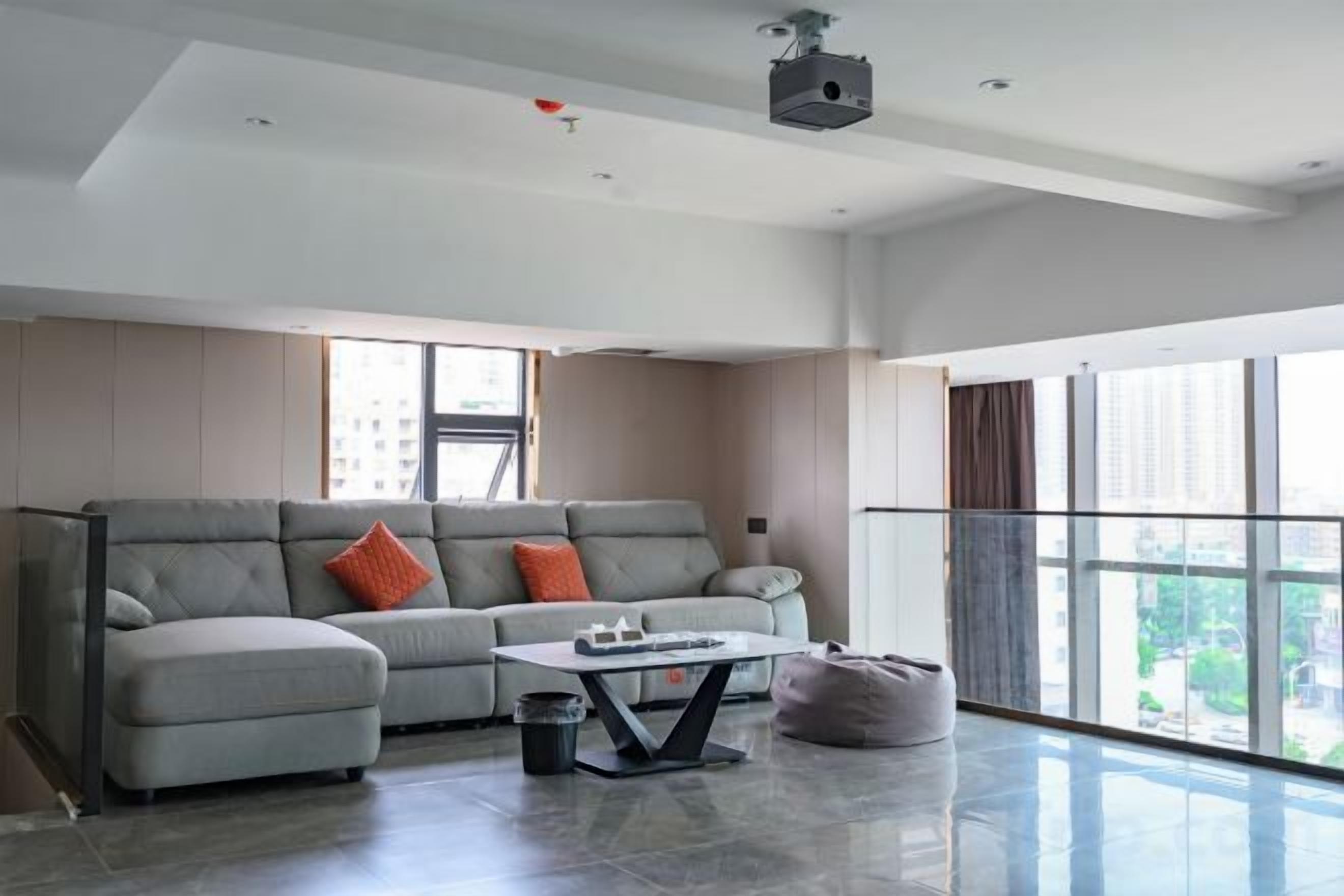 Una sala de estar moderna con un sofá gris, una mesa de centro y un ventanal grande.