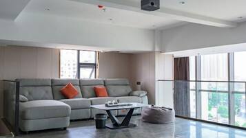 Una sala de estar moderna con un sofá gris, una mesa de centro y un ventanal grande.