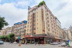 Un hotel de varios pisos con un estilo arquitectónico tradicional, que presenta una entrada destacada con un toldo rojo y un letrero.