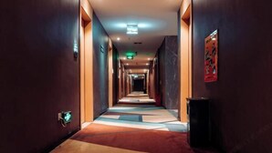 A hotel corridor with a geometric patterned carpet, recessed lighting, and a poster on the wall. - Heng Da Hotel (Yulin Railway Station Zhongyaogang) (Yulin)