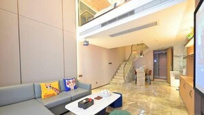A modern living room with a sofa, a coffee table, and a staircase leading to an upper level. - Heng Da Hotel (Yulin Railway Station Zhongyaogang) (Yulin)