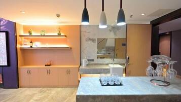 A modern kitchen with marble countertops, pendant lighting, and a wine rack.