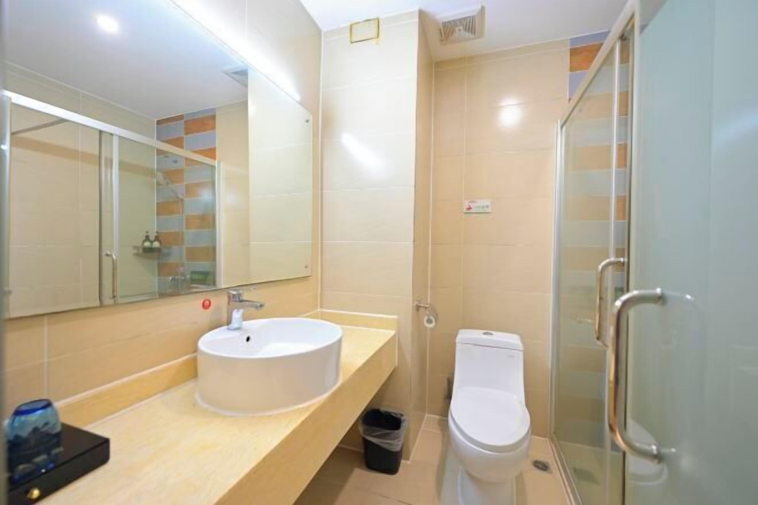 A modern bathroom with a sink, toilet, and glass shower enclosure.