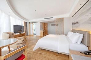 A hotel room with a bed, a desk, a chair, and a TV.