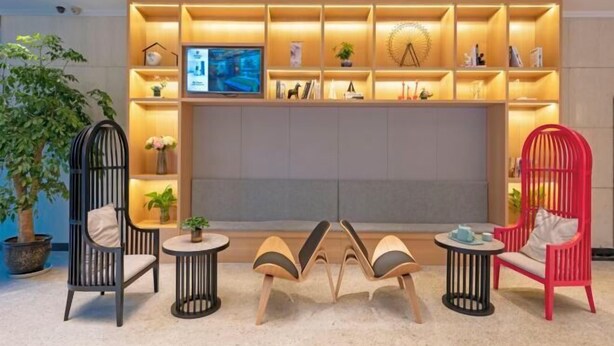 Un salon moderne doté d’un grand téléviseur, de nombreuses étagères ornées d’objets décoratifs et de différents types de sièges, notamment un fauteuil rouge et un fauteuil noir avec un coussin.