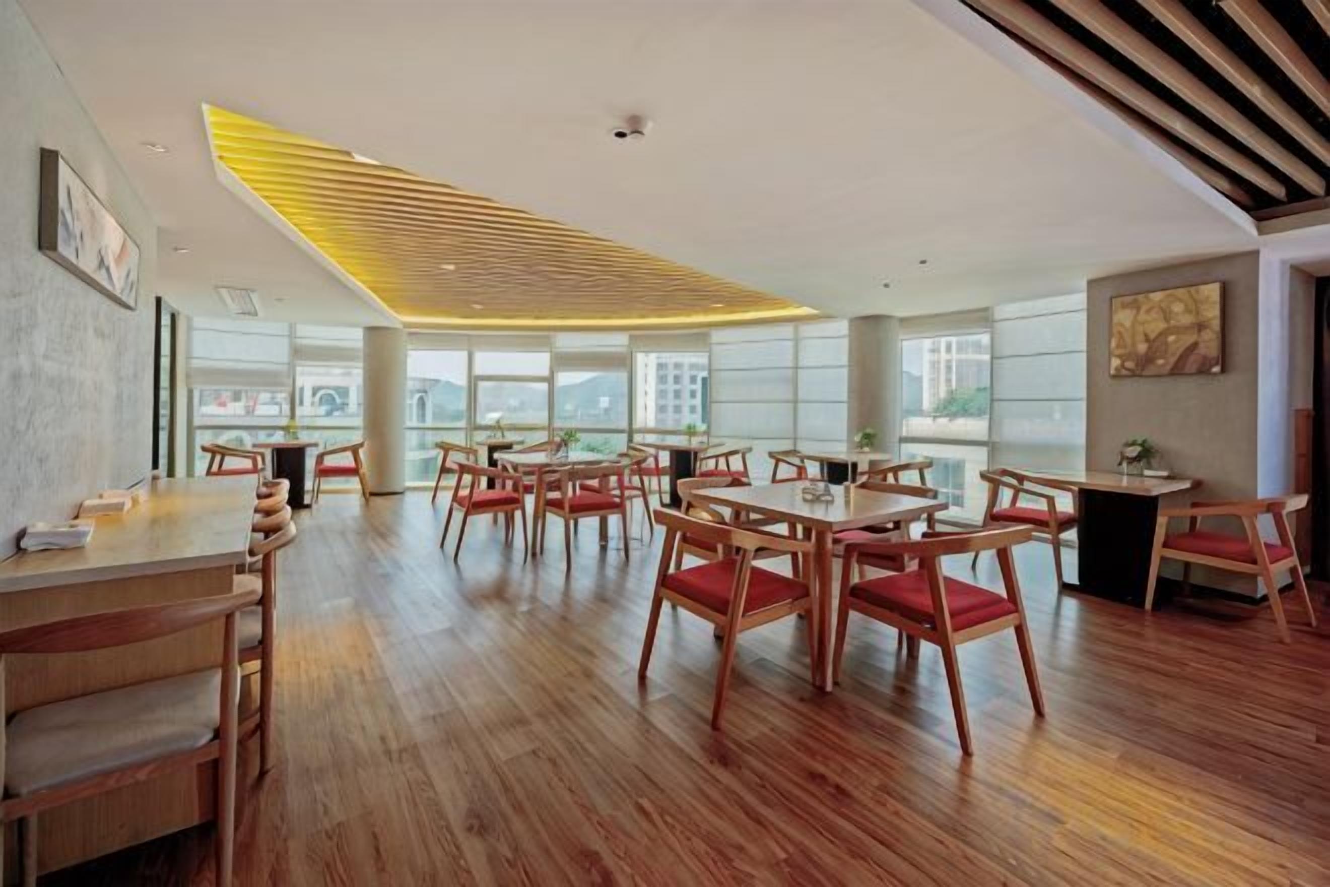 A spacious dining area with wooden flooring and multiple tables and chairs.