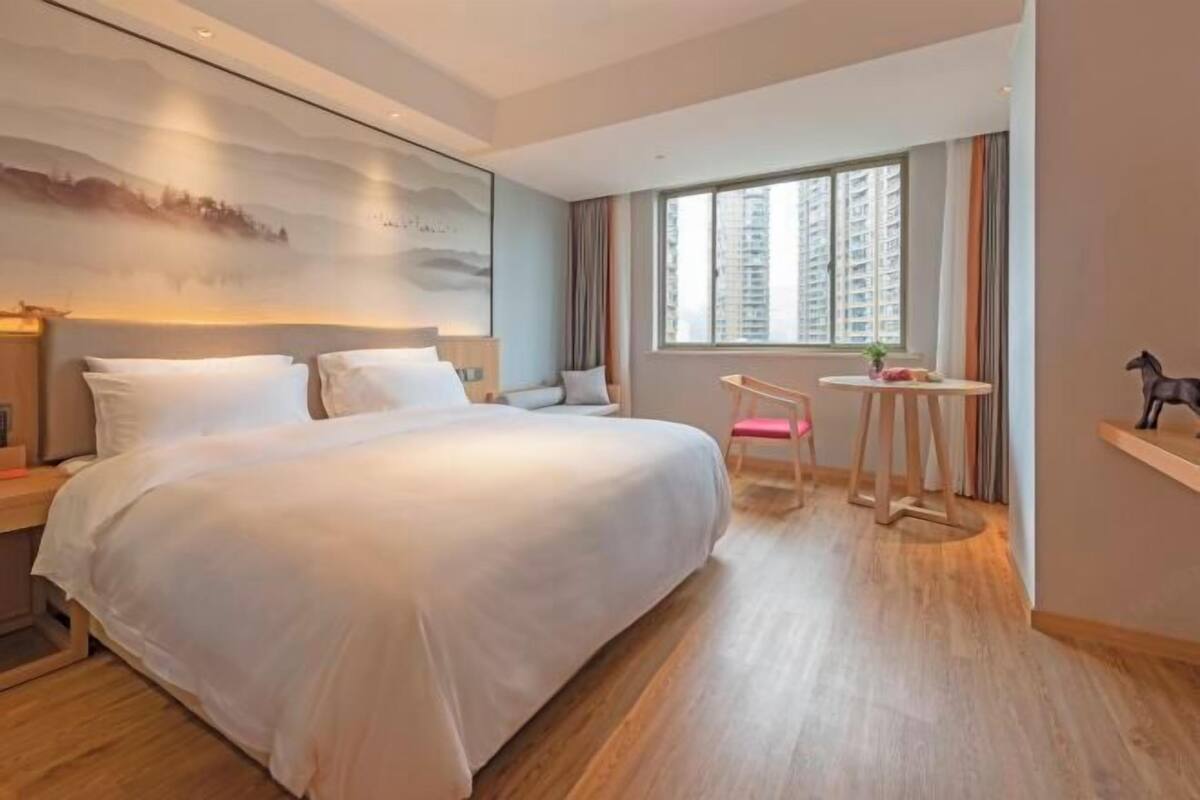 A modern hotel room with a large bed, a small table, and a chair.