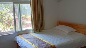 Een slaapkamer met een bed, een raam met gordijnen en een airconditioning aan de muur.