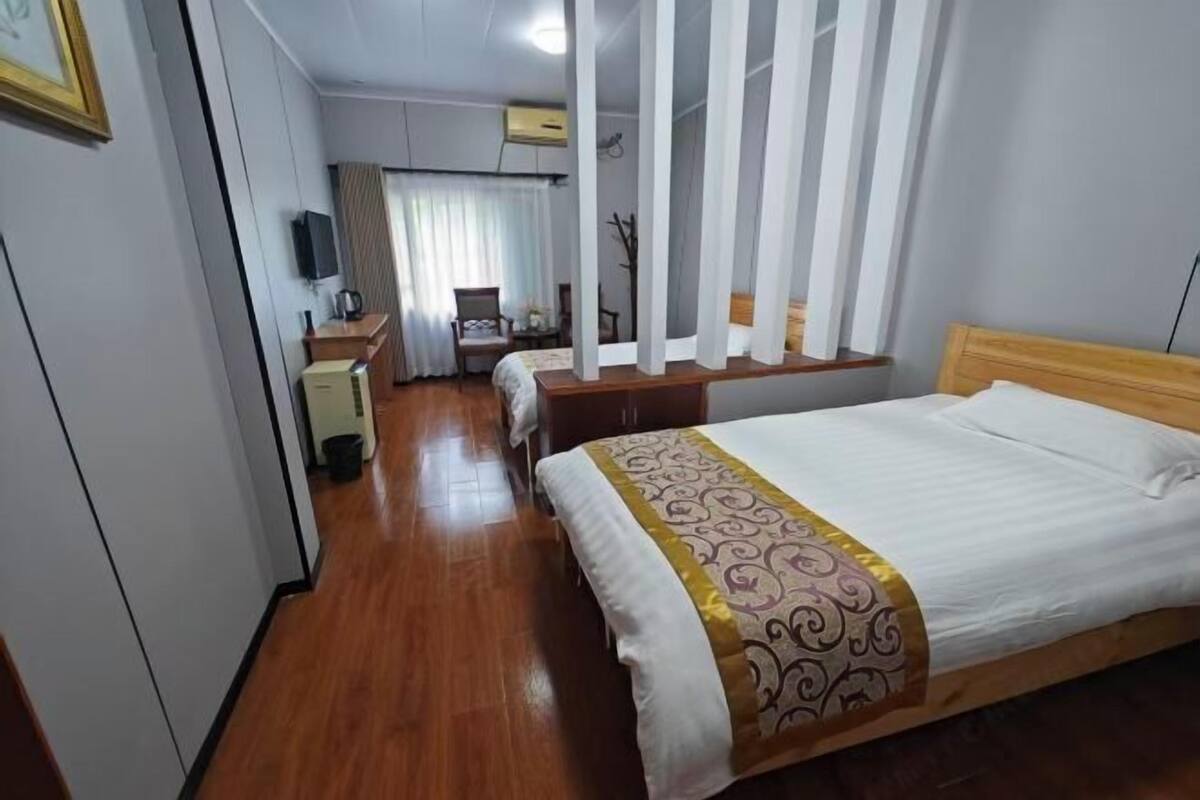 Hotelkamer met een bed, een bureau, een stoel, een televisie en een raam met gordijnen.