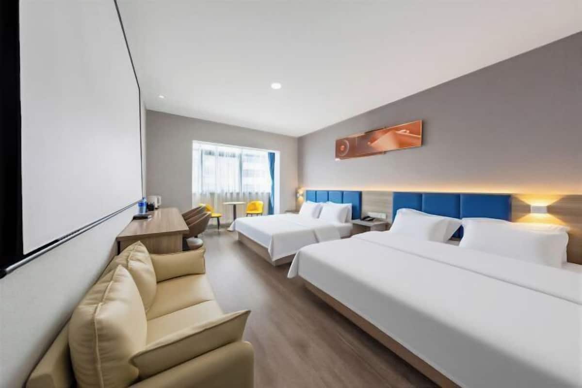 Une chambre d’hôtel avec deux lits, un canapé, un bureau et une fenêtre.