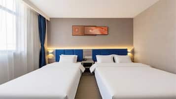 A hotel room with two beds, a headboard, a nightstand, and a wall-mounted TV.