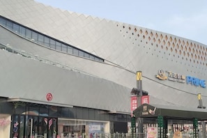 A modern building with a distinctive geometric roof design, a prominent signage for 'Prime,' and a storefront with a visible entrance. - 7 Days Premium Hotel (Tianjin Binhai Airport Zhangguizhuang) (Tianjin)