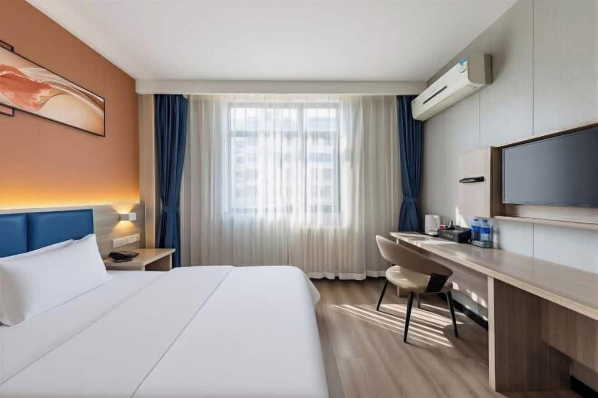 Une chambre d’hôtel équipée d’un lit, d’un bureau, d’une chaise et d’un téléviseur.