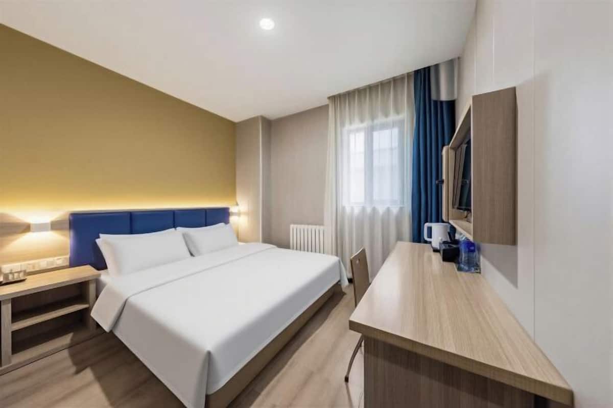 Une chambre d’hôtel comprenant un lit, une table de chevet, un bureau et un miroir.