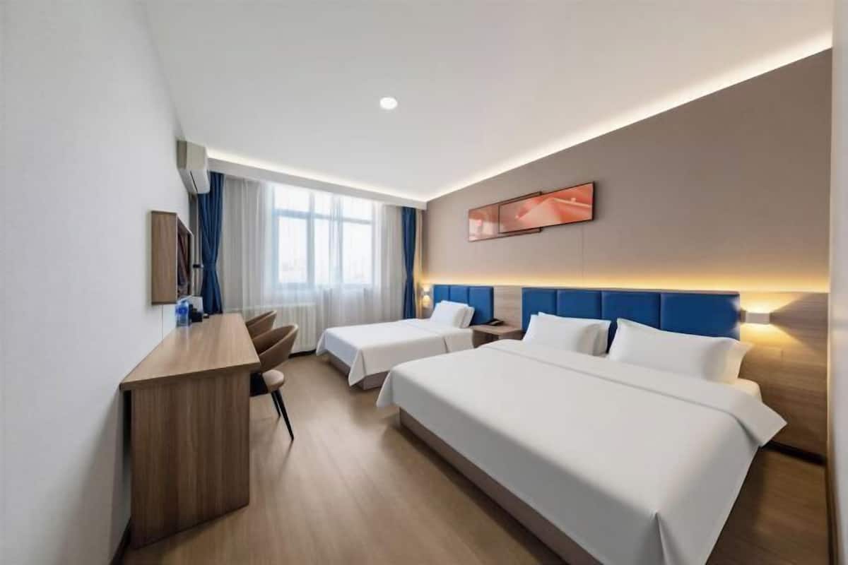 Une chambre d’hôtel avec deux lits, un bureau et une fenêtre avec des rideaux.