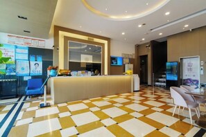 En hotellobby med en incheckningsdisk, sittplatser och ett rutmönstrat golv.