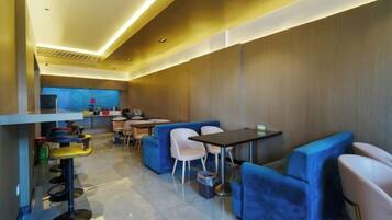 A modern interior with seating areas, tables, and a kitchen in the background.