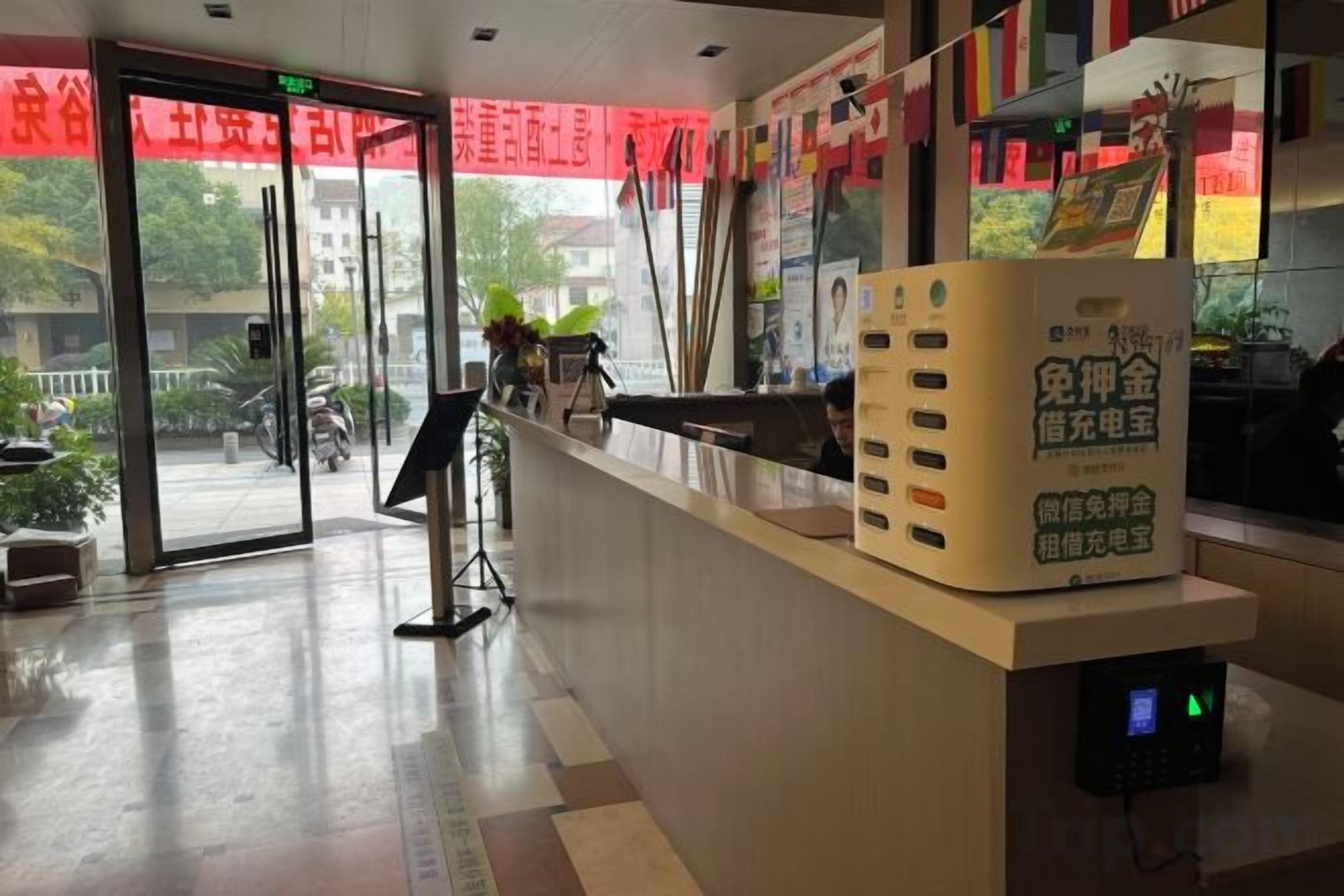 A reception desk with a digital display, a glass door entrance, and a red banner.