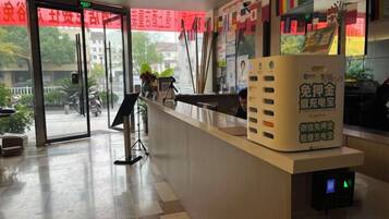 A reception desk with a digital display, a glass door entrance, and a red banner.