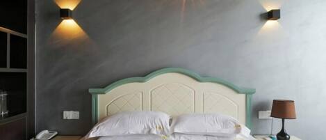 A neatly made bed with white linens, a cream-colored headboard, and two wall-mounted light fixtures on either side.