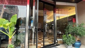 A hotel entrance with a glass door, potted plants, and a checkered floor. - Qingya Hotel (Jiaxing Wangdian) (Jiaxing)