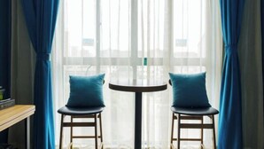 A room with a round table and two chairs, a window with sheer curtains, and a view of the outside. - Qingya Hotel (Jiaxing Wangdian) (Jiaxing)