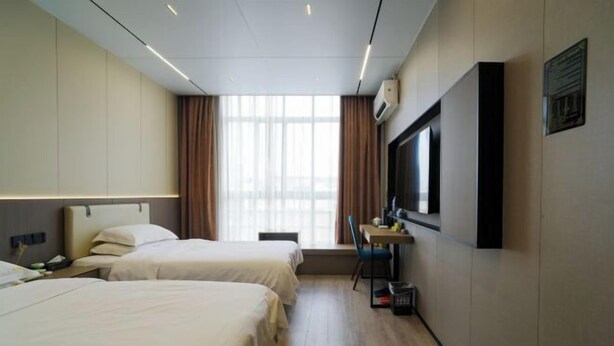 A hotel room with two beds, a desk, a chair, a TV, and a window with curtains. - Qingya Hotel (Jiaxing Wangdian) (Jiaxing)