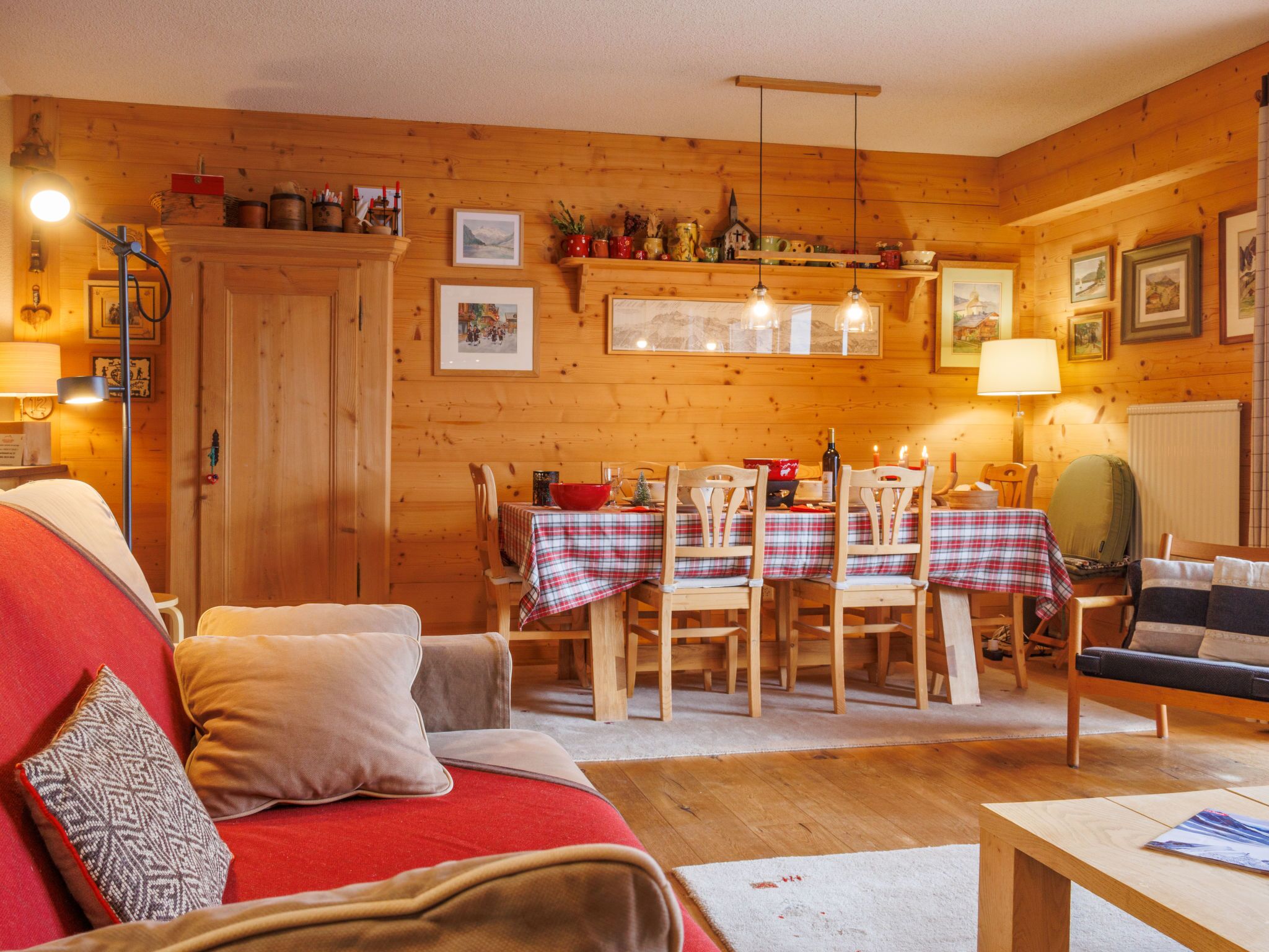 Een gezellig houten blokhutinterieur met een eethoek, houten wanden en een rode bank.