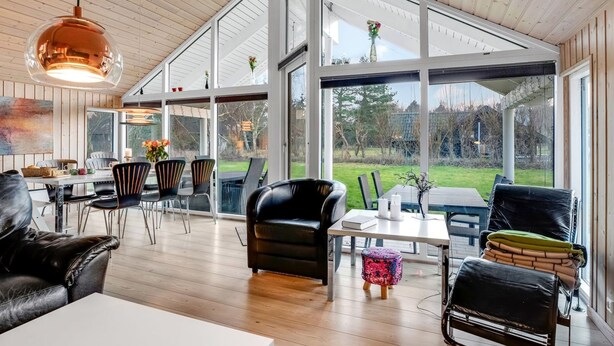 A spacious living area with a wooden ceiling, large windows, and modern furniture.