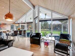 Un vaste espace de vie doté d’un plafond en bois, de grandes fenêtres et de meubles modernes.