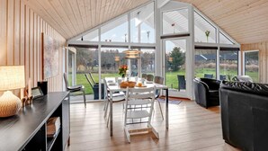 A spacious dining area with a high ceiling and large windows, offering views of the outdoors.