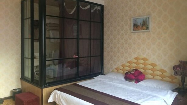 A bedroom with a bed, a wardrobe, and a painting on the wall. - qinggangxian yinzuo shishangbinguan (Qinggang)
